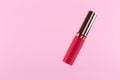 Lipstick levitation on pastel pink background. Liquid lip stick red lip gloss open tube. Makeup cosmetic product. Top view, flat Royalty Free Stock Photo