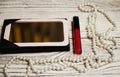 Lipstick and pearls on white table Royalty Free Stock Photo