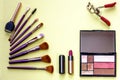 Lipstick, powder box, eyelash curler, makeup brush set on a yellow background. The concept of fashion and beauty. Royalty Free Stock Photo