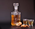 A liqueur based on a walnut on a black background, next to a bottle, two glasses of a drink and nuts Royalty Free Stock Photo