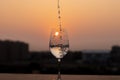 Liquid being poured into a wine glass at sunset