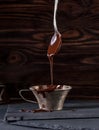 Liquid chocolate dripping from spoon into cup