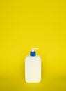 Liquid container for gel, lotion, cream, shampoo, bath foam. Cosmetic plastic bottle with blue dispenser pump on yellow Royalty Free Stock Photo