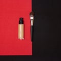 Liquid fluid make-up foundation bottle with professional makeup brush on red and black background. Top view, flatlay Royalty Free Stock Photo