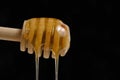 Liquid and fresh honey dripping from wooden honey spoon black background. Royalty Free Stock Photo