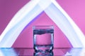 Liquid with ice in a glass on a reflective surface on a reddish background Royalty Free Stock Photo