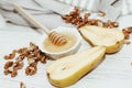 Liquid organic honey in white bowl with pears, wooden honey spoon.