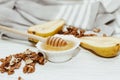 Liquid organic honey in white bowl with pears, wooden honey spoon.