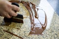 Liquid tempered chocolate applied in a thin layer on a granite table for it cooling