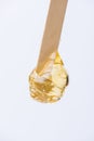 Liquid yellow sugar paste or wax for depilation on a stick close-up on a white background