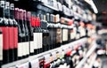 Liquor store, alcohol shop. Red wine on shelf. Focus on bottles, supermarket aisle in background. Royalty Free Stock Photo