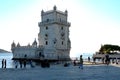 Lisbon, Belem tower or Torre de Belem with blue river in the background and tourists, visitors in the foreground