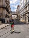 Youth riding a Lime electric scooter along Lisbon street
