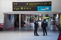 Lisbon, Portugal - December 15, 2019 - Two police woman talking in the airport. Sign with information in the building of airport
