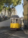 Lisbon, Portugal, October 24, 2021: View of steep narrow Lisbon street with typical yellow vintage tram number 28 line Royalty Free Stock Photo