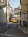 Lisbon, Portugal, October 24, 2021: View of steep narrow Lisbon street with typical yellow vintage tram number 28 line Royalty Free Stock Photo