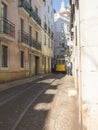 Lisbon, Portugal, October 24, 2021: View of steep narrow Lisbon street with typical yellow vintage tram number 28 line Royalty Free Stock Photo