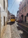 Lisbon, Portugal, October 24, 2021: View of steep narrow Lisbon street with typical yellow vintage tram number 28 line Royalty Free Stock Photo