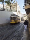 Lisbon, Portugal, October 24, 2021: View of steep narrow Lisbon street with typical yellow vintage tram number 28 line Royalty Free Stock Photo