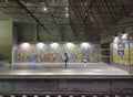 Lisbon subway station with murals and a girl speaking at the phone