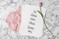 List of baby names tulip flower and child\'s clothes on white marble background flat lay