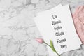 List of baby names tulip flower and child\'s clothes on white marble background flat lay. Space for text