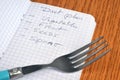 Diet plan concept with a list written in a notebook next to a fork close up Royalty Free Stock Photo