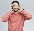 Listen, happy and Asian man with headphones, streaming music and sounds against a white studio background. Japan, male