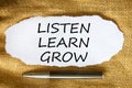 Words `Listen, learn, grow on white paper. Black metallic pen. Beautiful canvas background.