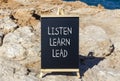 Listen learn lead symbol. Concept word Listen Learn Lead on beautiful black chalk blackboard. Beautiful stone beach sea blue Royalty Free Stock Photo