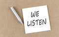 WE LISTEN text on sticky note on a cork board with pencil Royalty Free Stock Photo