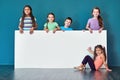 Listen up, the kids have something to say. Studio portrait of a diverse group of kids standing behind a large blank Royalty Free Stock Photo