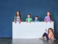 Listen up, the kids have something to say. Studio shot of a diverse group of kids standing behind a large blank banner Royalty Free Stock Photo