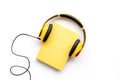 Listening audio books with headphones in library on wooden background top view