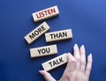 Listening skills symbol. Concept words Listen more than you Talk on wooden blocks. Businessman hand. Beautiful deep blue Royalty Free Stock Photo