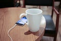 Listening to music on a smartphone while drinking coffee alone in a cafe Royalty Free Stock Photo