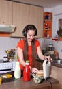 She listens to music as he puts sandwiches in toast machine.