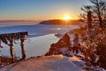 Listvyanka, Russia - February 21 2019: Veiw at Baikal lake at sunset with trees and rocks from a mountain peak Royalty Free Stock Photo