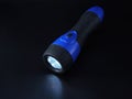Lit black and blue LED flashlight on black background Royalty Free Stock Photo