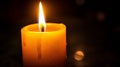 Lit candle with a bright flame and melting wax, against a dark background, evoking warmth and tranquility Royalty Free Stock Photo