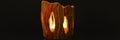 the lit candle burns inside the candlestick on a black background. beautiful fire light from the slits of a candleholder made of c