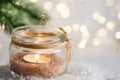 Lit candle in crystal jar candleholder hanging Christmas tree branch in snow in winter forest. New Year Royalty Free Stock Photo