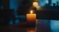 A lit candle sits on a smooth, polished table, casting a warm glow in a dimly lit room