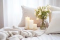 Lit candles on a tray beside a vase of fresh white flowers on a cozy bed with soft pillows. Good morning concept Royalty Free Stock Photo