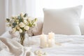 Lit candles on a tray beside a vase of fresh white flowers on a cozy bed with soft pillows. Good morning concept Royalty Free Stock Photo