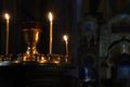 Lit church candles in a gilded candlestick in a temple in the dark. yellow wax lighted candles stand in the church, glow Royalty Free Stock Photo