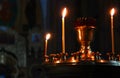 Lit church candles in a gilded candlestick in a temple in the dark. yellow wax lighted candles stand in the church, glow Royalty Free Stock Photo