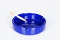 A lit cigarette in a blue ahtray Royalty Free Stock Photo