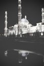 Lit city mosque with reflection in the surface of puddle on the Royalty Free Stock Photo