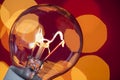 Lit electrical light bulb with warm red background